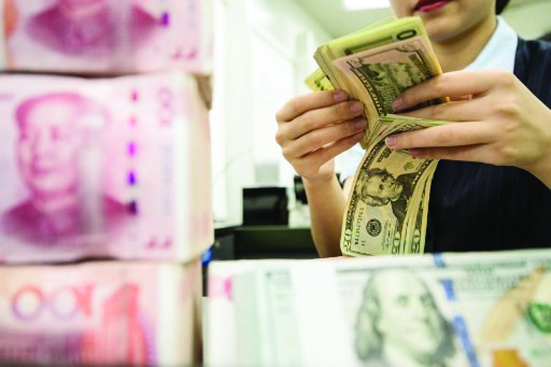 NANTONG: A Chinese bank employee counts 100-yuan notes and US dollar bills at a bank counter in Nantong in China's eastern Jiangsu province.-AFPnnn