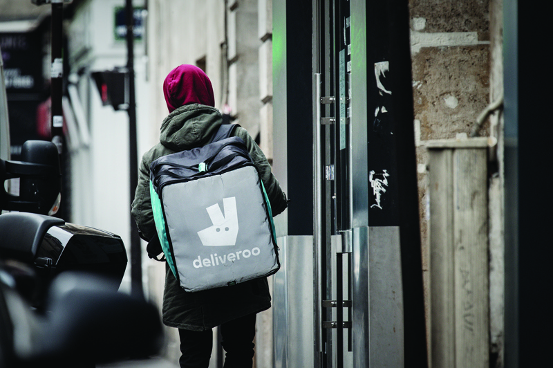 PARIS: In this file photo, a man working for the food delivery company Deliveroo looks for his delivery address in an empty street in Paris.-AFPn