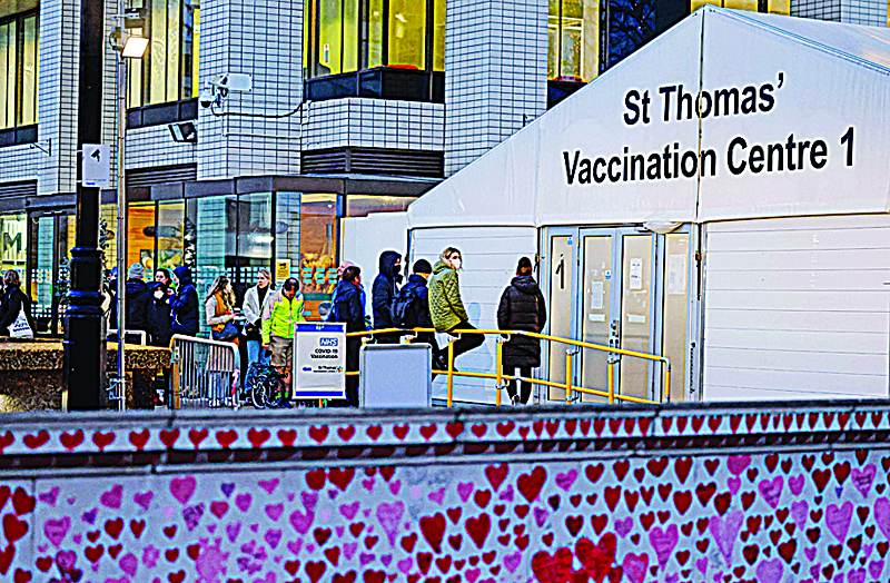 LONDON: Members of the public are pictured beyond hearts painted on the National COVID Memorial Wall, as they queue to receive a dose of a COVID-19 vaccine outside a coronavirus vaccination centre outside Guy's and St Thomas' Hospital in central London yesterday. - AFPn