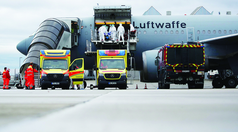 DRESDEN: Medics wearing PPE suits transfer patients infected with the coronavirus into the Airbus A310-900 MRTT MedEvac Hermann Koehl of the German armed forces Bundeswehr before they are airlifted and transported to other intensive care units (ICU) yesterday. - AFP n