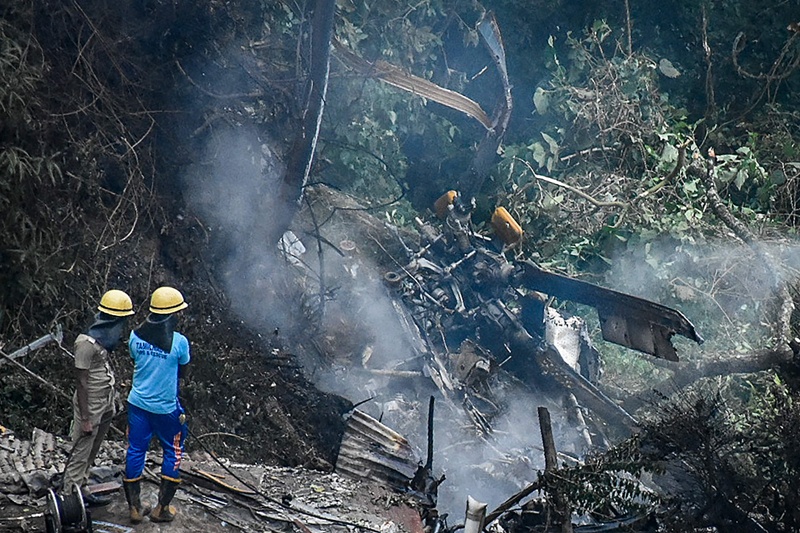 COONOOR, India: Firemen and rescue workers stand next to the debris of an IAF Mi-17V5 helicopter after it crashed yesterday. - AFP n