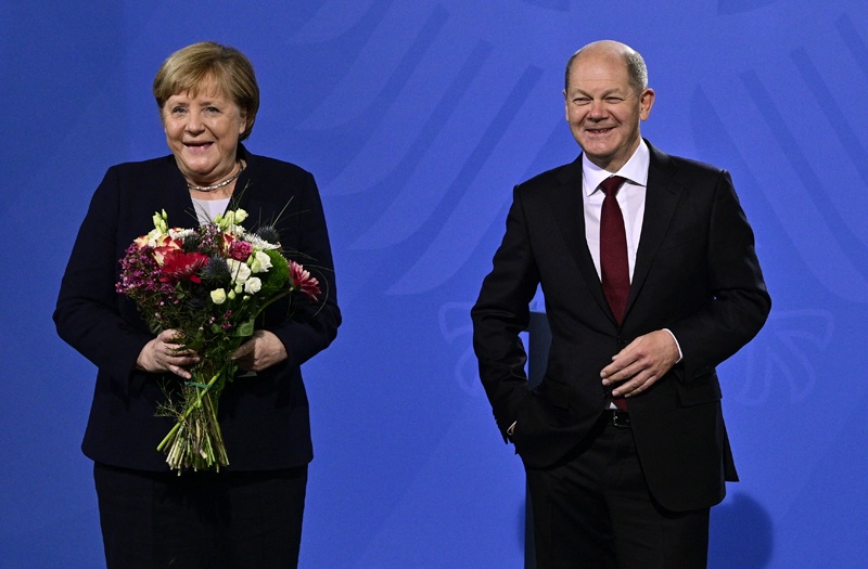 BERLIN: German Chancellor Olaf Scholz and his predecessor Angela Merkel pose after Scholz gave Merkel a bouquet of flowers during a handover ceremony at the Chancellery yesterday. - AFP n