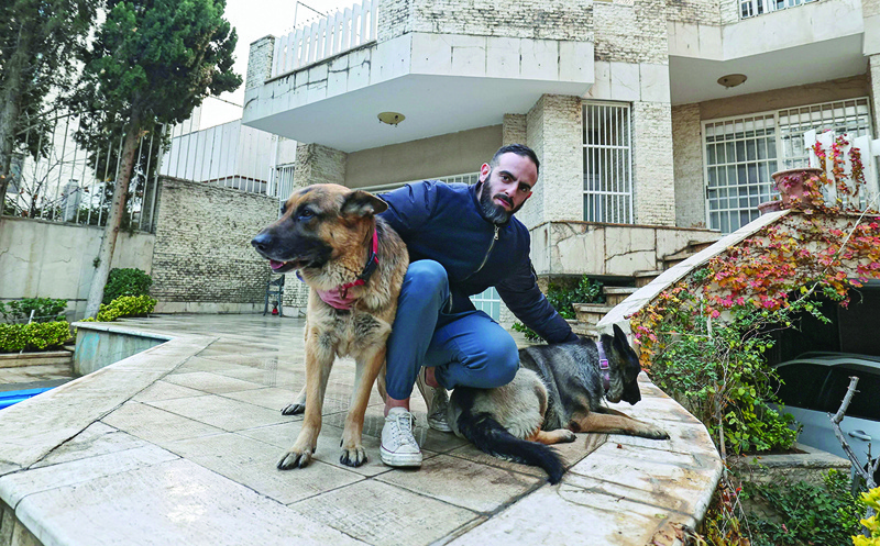 TEHRAN: An Iranian man poses for a picture with his dogs in a yard near his house on Dec 5, 2021. - AFP 