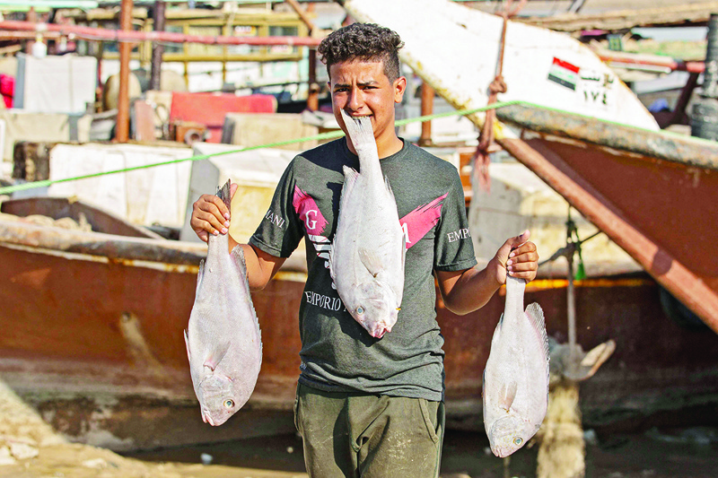 AL-FAW, Iraq: An Iraqi youth carries freshly-caught fish in this southern Iraqi port city on Oct 26, 2021. - AFP n