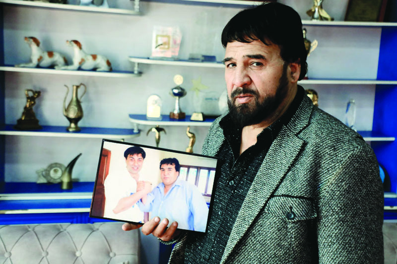 Afghan film director Salim Shaheen displays a print of him posing with Indian Bollywood actor Sunny Deol, during an interview with AFP in his residence in Kabul. - AFPn
