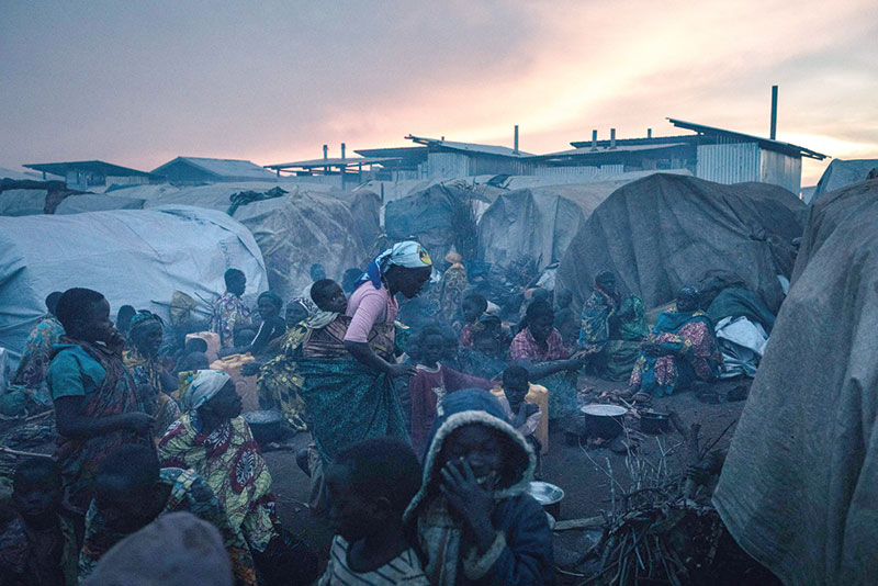 BUNIA, DR Congo: Displaced women and children prepare food at sunset in the Rhoo IDP camp. Since late November, several villages and IDP camps have been attacked and nearly 100 people have been killed in the area, forcing up to 70,000 people to gather on the Rhoo hill around a base of Bangladeshi peacekeepers from Monusco. —AFP