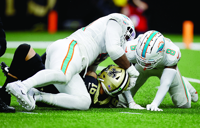 NEW ORLEANS: Ian Book #16 of the New Orleans Saints is sacked by Jevon Holland #8 and Emmanuel Ogbah #91 of the Miami Dolphins in the fourth quarter of the game at Caesars Superdome on December 27, 2021. — AFP