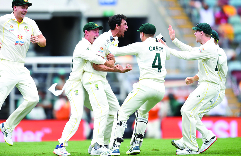 BRISBANE: Mitchell Starc of Australia (center) celebrates taking the wicket of England's Rory Burns with the first ball of the match during day one of the first Ashes cricket Test match between England and Australia yesterday. - AFP n