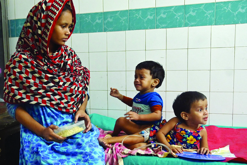 DHAKA: The conjoined twins Lamisa (R) and Labiba sit beside their mother Monufa on the eve of their surgery at a hospital in Dhaka yesterday. - AFPnn