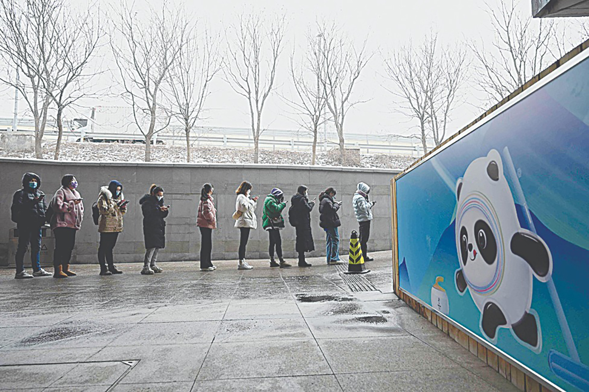 BEIJING: People queue next to a poster of Bing Dwen Dwen, mascot of the Beijing 2022 Olympic Games, to have their swab samples taken to test for the COVID-19 oronavirus in Beijing yesterday. - AFP