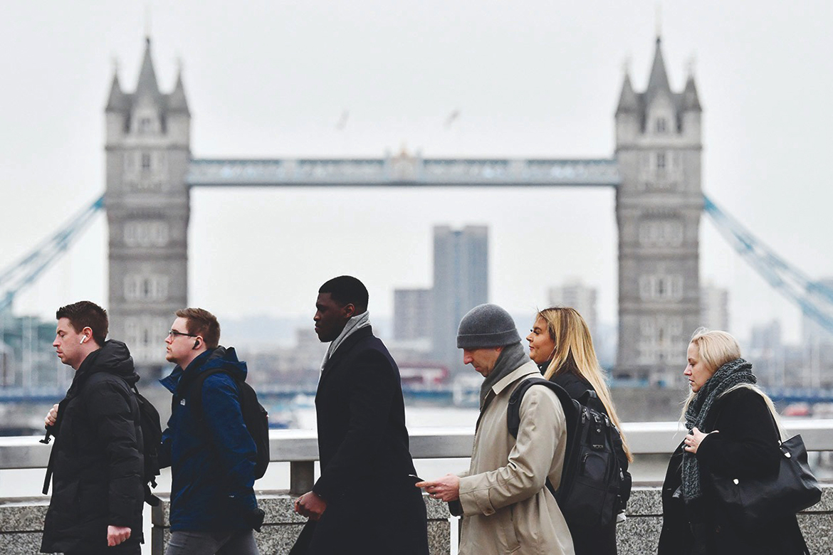 LONDON: Pedestrians on their way to work cross the London Bridge backdropped by the Tower Bridge yesterday. - AFP