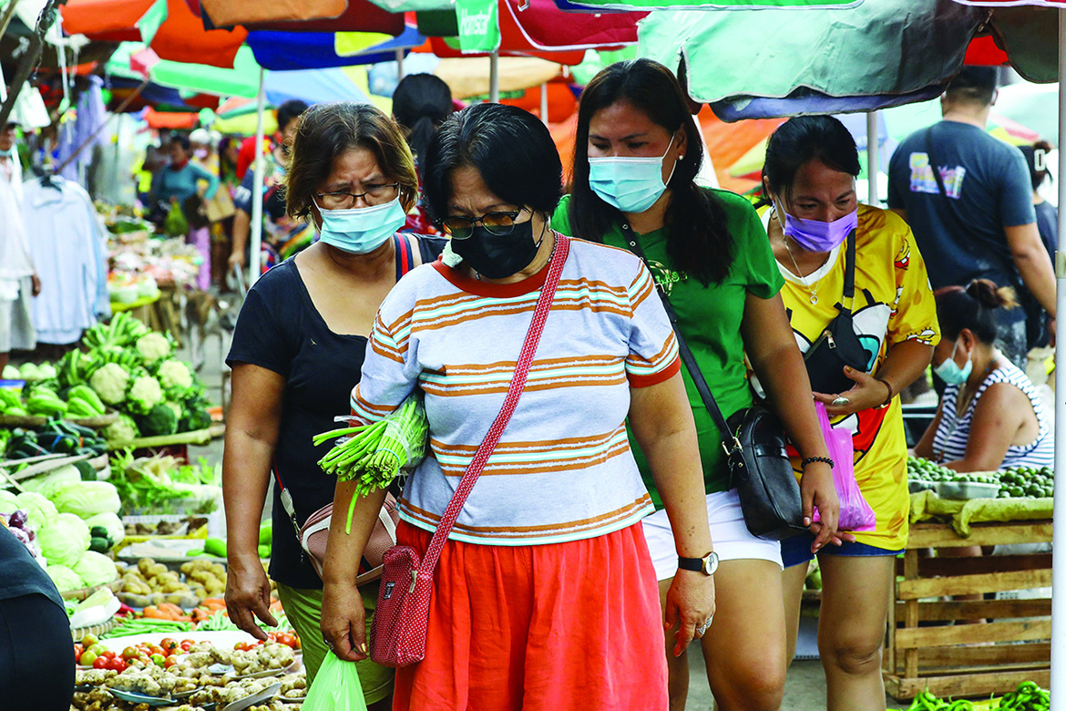 QUEZON CITY: People walk past vegetables on sale at a market in Quezon city, suburban Manila. – AFP