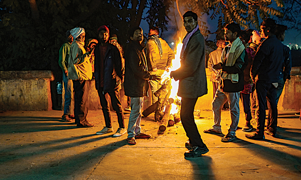 NEW DELHI: In this picture taken on Saturday shows homeless people gathered besides a bonfire to keep themselves warm in a wintry evening in New Delhi. —AFP