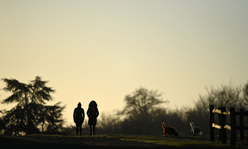 People walk their dogs in the early morning sun on a winter’s day in Richmond Park, south west London yesterday. — AFP photos