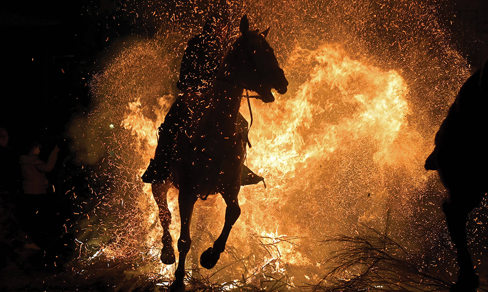 Horsemen ride through a bonfire in the village of San Bartolome de Pinares in the province of Avila in central Spain, during the traditional religious festival of ëLas Luminariasí in honor of San Antonio Abad (Saint Anthony), patron saint of animals. — AFP photos