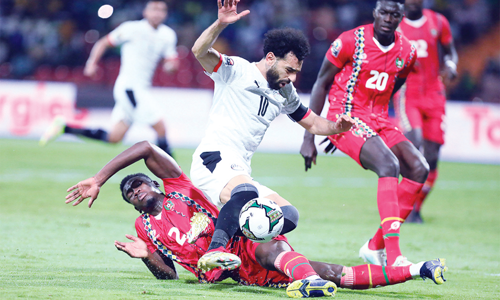 TOPSHOT - Egypt's forward Mohamed Salah (R) is fouled by Guinea-Bissau's defender Fali Cande  during the Group D Africa Cup of Nations (CAN) 2021 football match between Guinea-Bissau and Egypt at Stade Roumde Adjia in Garoua on January 15, 2022. (Photo by Daniel BELOUMOU OLOMO / AFP)
