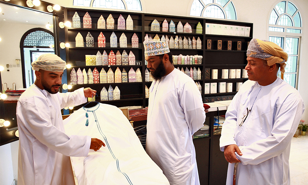 An Omani tailor displays a Dishdasha at a shop in the Omani capital Muscat. — AFP photos