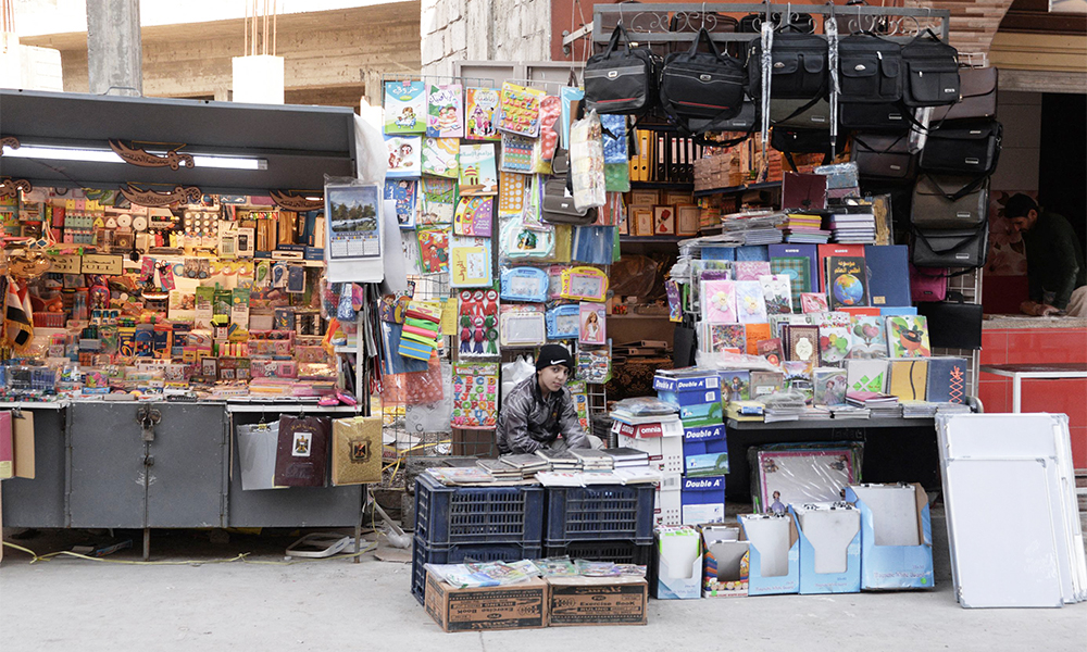 An Iraqi youth sits at a stall for books and school supplies in Iraq’s northern city of Mosul.