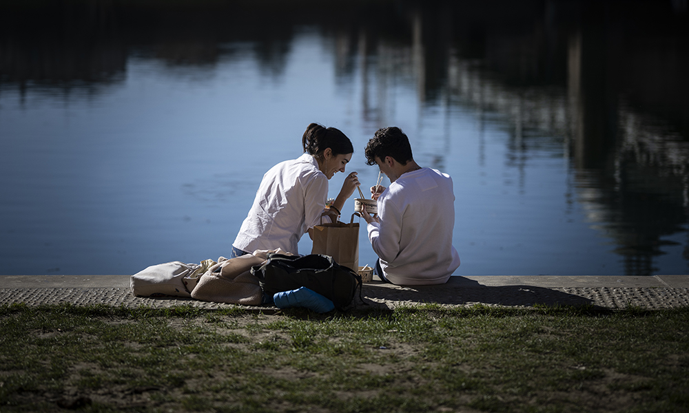 A couple shares food on the Garonne river bank in Toulouse, southwestern France on February 8, 2022.