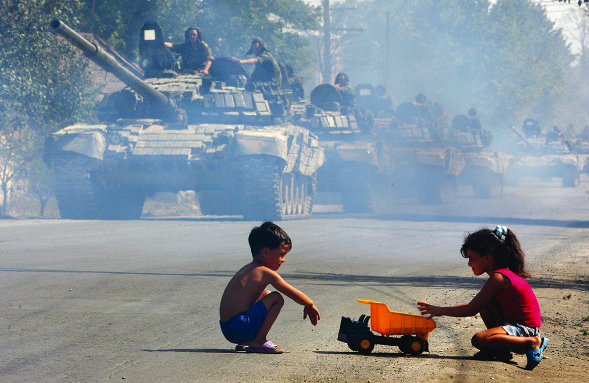 TSKHINVALI, Georgia: In this file photo taken on August 30, 2008 Russian tanks move along a street as children play with a toy truck in Tskhinvali. - AFP