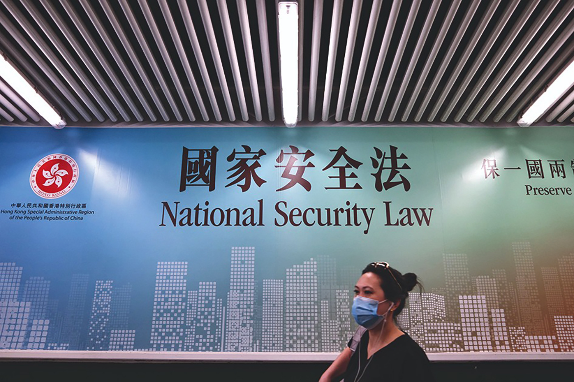HONG KONG: Photo shows a woman walking past a poster for the National Security Law in Hong Kong. The national security law imposed by Beijing in 2020 to snuff out dissent has knee-capped Hong Kong's civil society sector. - AFP