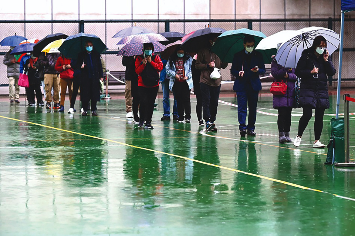 HONG KONG: People queue up for COVID-19 tests in pouring rain in Hong Kong yesterday, as the city faces its worst coronavirus wave to date. – AFP