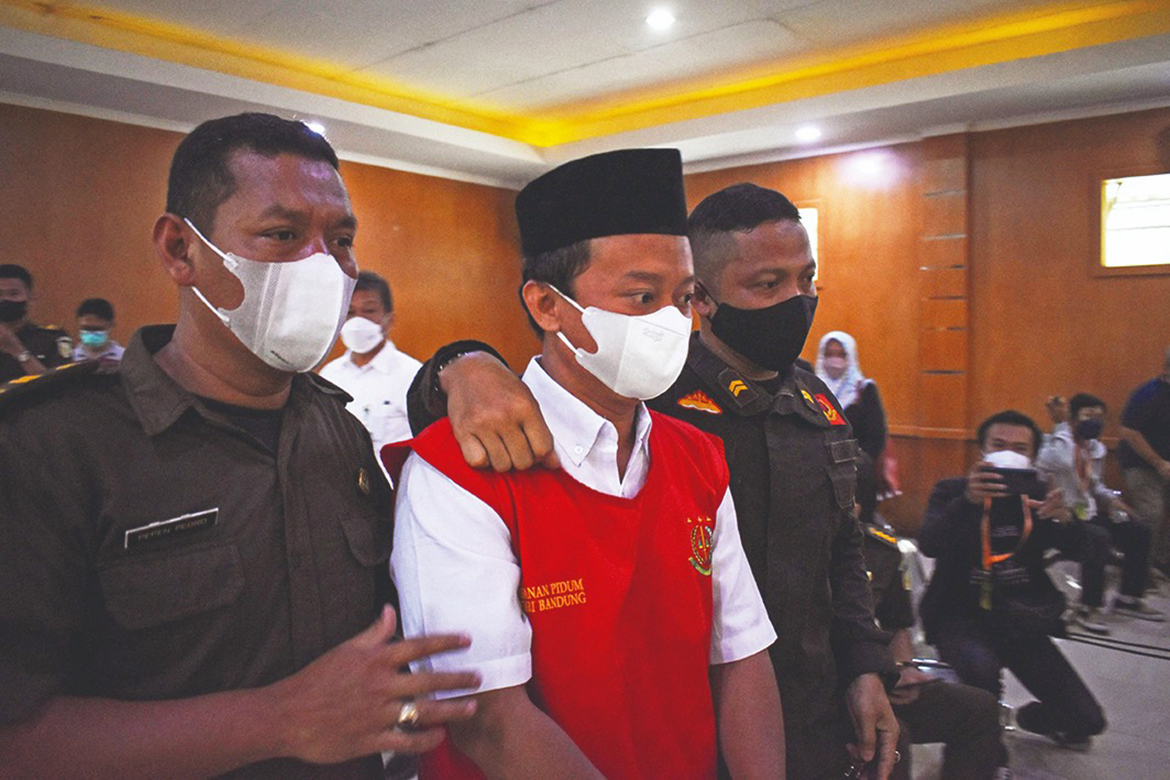 BANDUNG, Indonesia: Indonesian teacher Herry Wirawan (C) is escorted prior to his trial at a court in Bandung, West Java yesterday, where he was later sentenced to life in prison for the rape of 13 students, all minors. – AFP