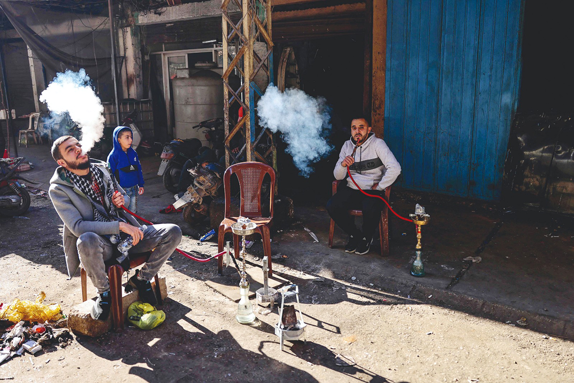 TRIPOLI: Lebanese men smoke waterpipes as they take a break outside their workshop in an alley of the northern city of Tripoli's impoverished neighborhood of Bab al-Tabbaneh. - AFP