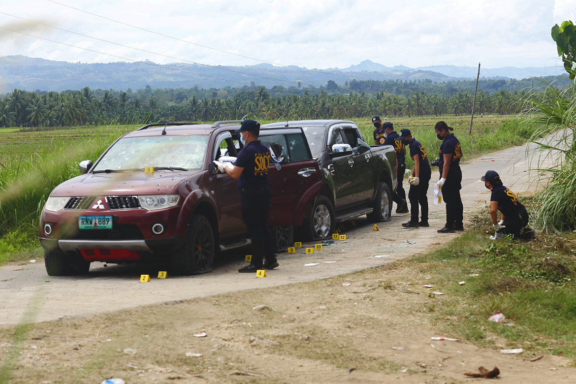 GUINDULUNGAN, Philippines: Philippine police investigators look for evidence next to bullet-riddled vehicles after a convoy of SUVs was ambush along a farm-lined road in Guindulungan town, Maguindanao province, in the southern island of Mindanao yesterday, leaving nine people dead. - AFP