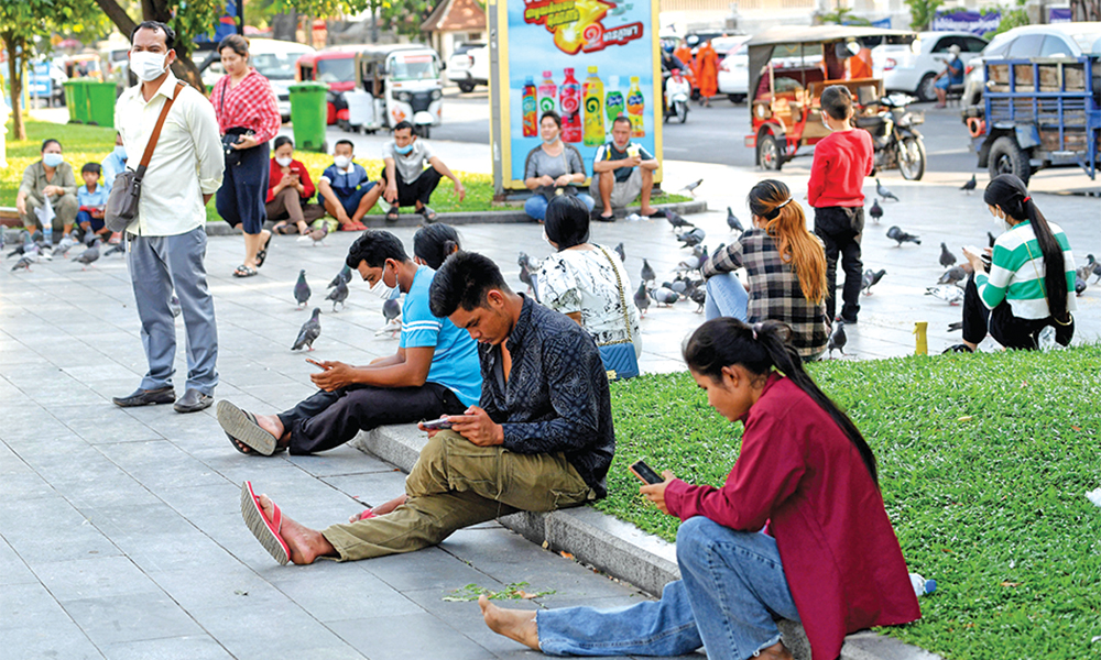 PHNOM PENH, Cambodia: This photo taken on February 4, 2022 shows people using their smartphones in a park in Phnom Penh. Cambodia is powering up its new national internet gateway, a move activists say will allow the government to further silence the countryís embattled opposition voices. — AFP