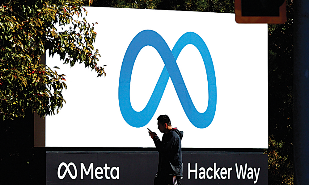 MENLO PARK, US: In this file photo, a pedestrian walks in front of a new logo and the name ‘Meta’ on the sign in front of Facebook headquarters in Menlo Park. —AFP