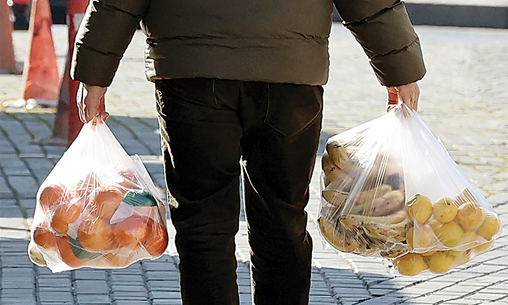 ANKARA: A man carries bags of fruits he bought from an open market in Ankara. —AFP