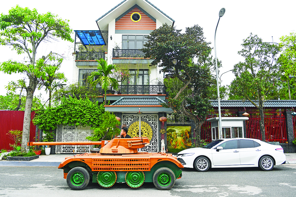 Truong Van Dao rides past a house in a wooden tank made from the conversion of an old minibus in a residential area in Bac Ninh province.—AFP photos