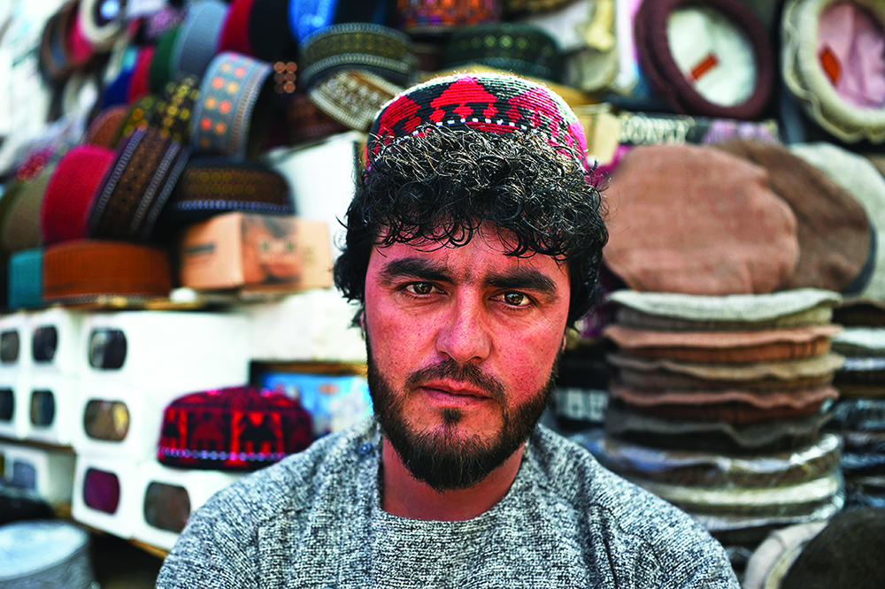 An Afghan hat vendor wearing an Uzbek cap waits for customers at his stall in a market near the Pul-e Khishti Mosque in Kabul. - AFP photosn