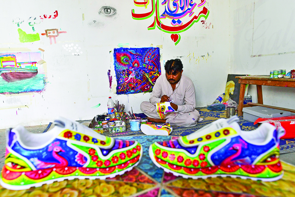 In this picture truck artist Haider Ali works on a pair of sneakers at his workshop in Karachi. –AFP photosn