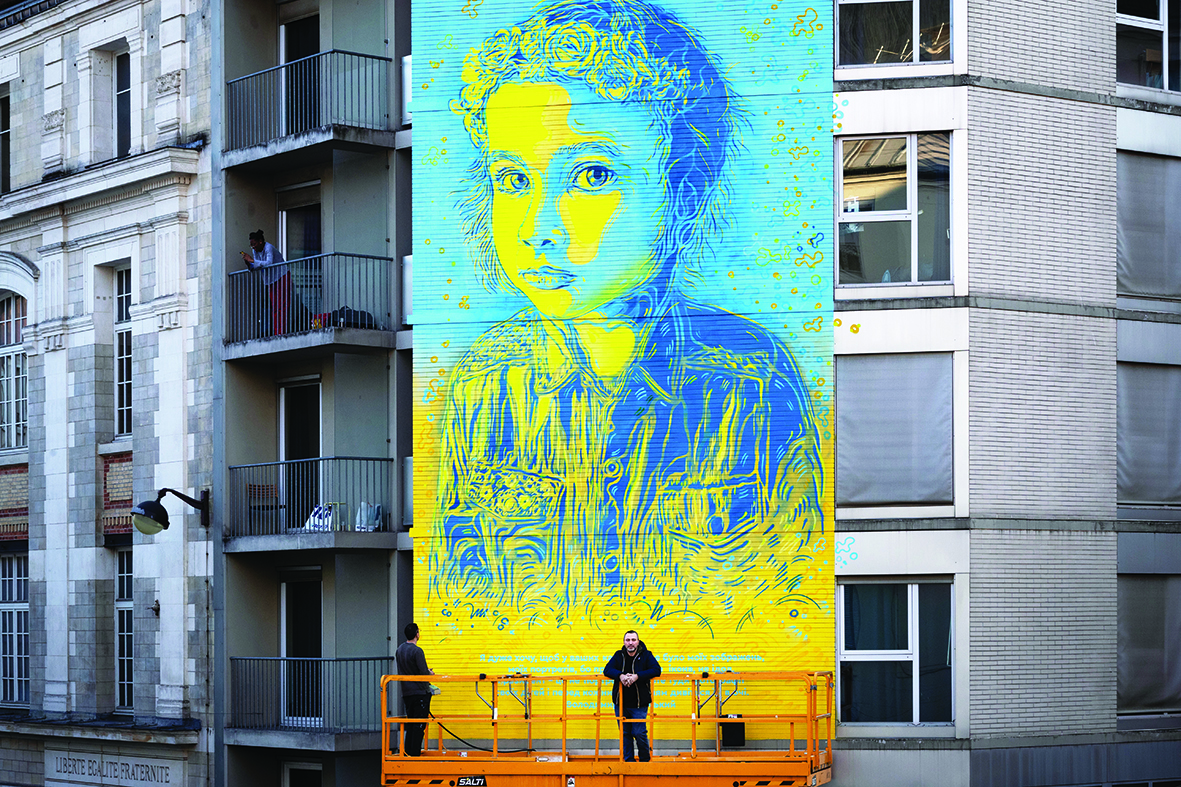 French street artist and painter Christian Guemy (right) known as C215 poses in front of his fresco depicting a Ukrainian young girl with a quote attributed to Ukrainian President Volodymir Zelensky.—AFP  n