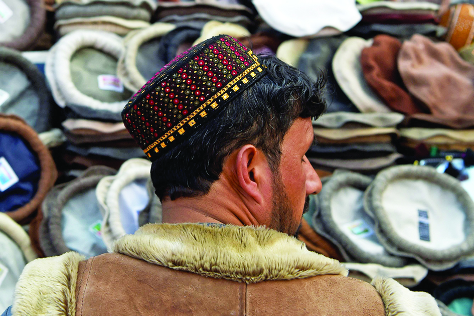 An Afghan man walks in a market wearing a Kandahari hat in Kabul.<br>