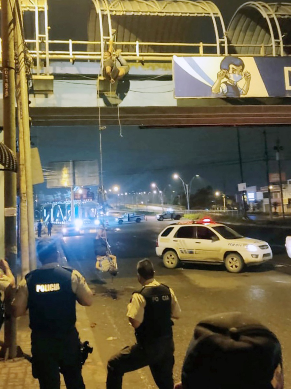 DURAN: Police officers look at two bodies hanging from a pedestrian bridge in Duran, Guayas province, Ecuador. The brutality of drug traffickers is cornering Ecuador after being safe from its violence. - AFP