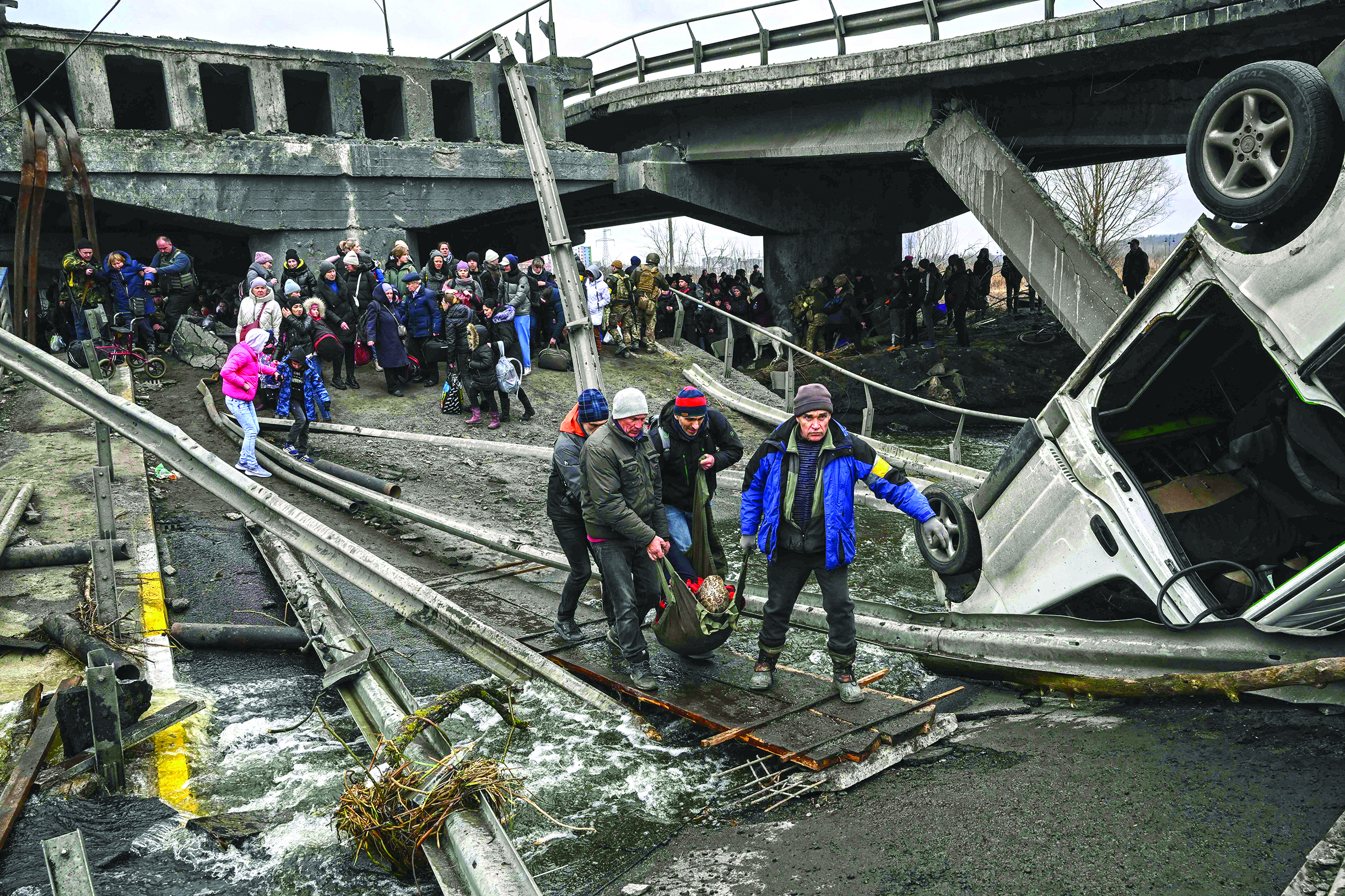 IRPIN, Ukraine: People cross a destroyed bridge as they evacuate this city northwest of Kyiv during heavy shelling and bombing yesterday. - AFP n