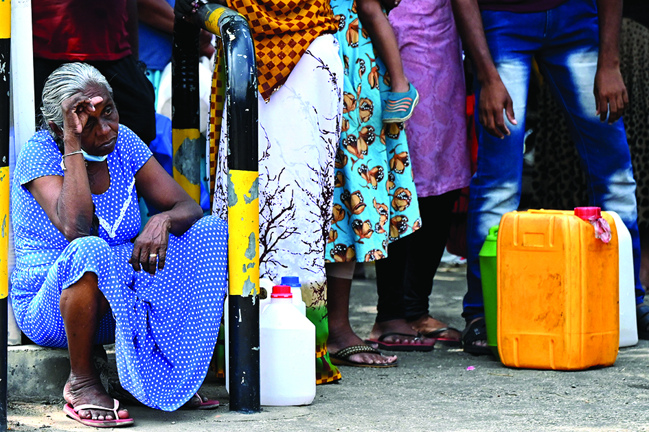 COLOMBO: A woman waits in a queue to buy kerosene for home use at a service station in Colombo. - AFP