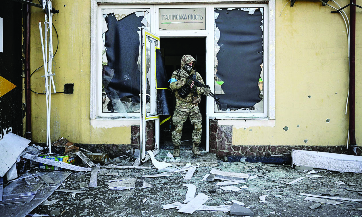 KYIV: A Ukrainian serviceman exits a damaged building after shelling in the capital yesterday. - AFP n
