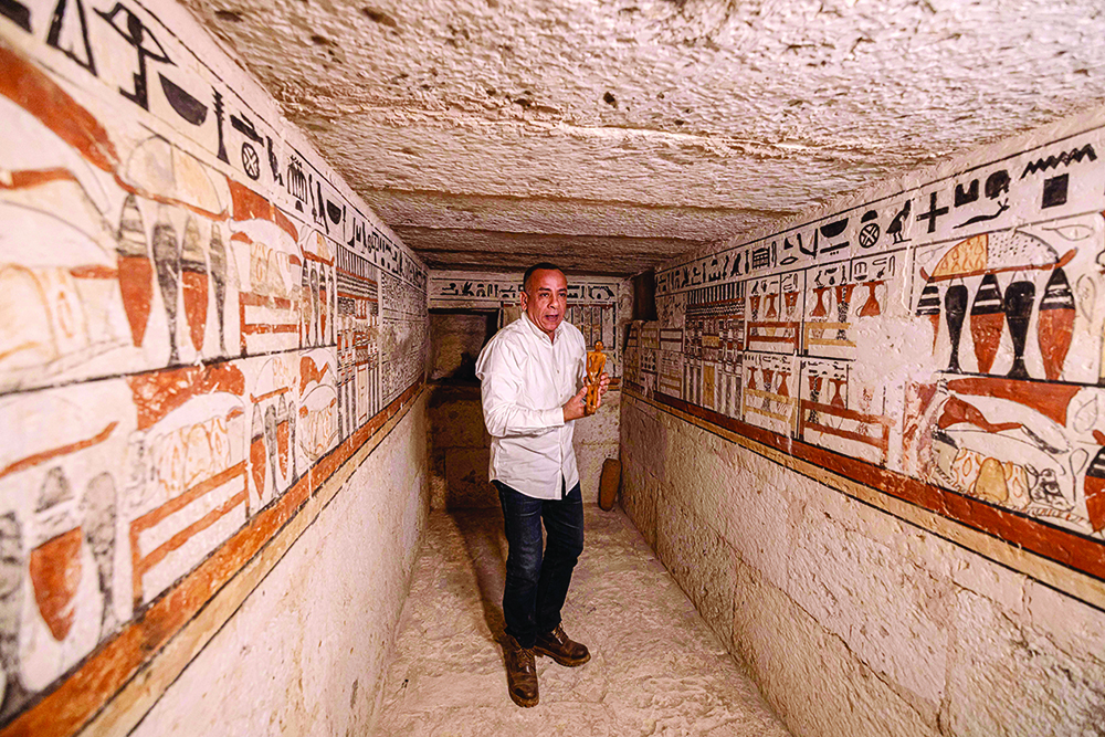 SAQQARA, Egypt: Mostafa Waziri, head of Egypt's Supreme Council of Antiquities, holds a small statuette yesterday inside one of five ancient Pharaonic tombs recently discovered at this archaeological site. - AFP n