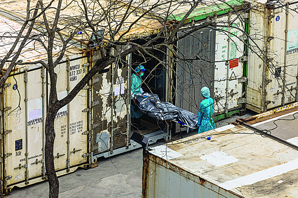 HONG KONG: Workers move the body of deceased person from a truck into a refrigerated container at the Fu Shan Public Mortuary in Hong Kong yesterday amid the city's worst-ever COVID-19 coronavirus outbreak that has seen overflowing hospitals and morgues and a frantic expansion of the city's spartan quarantine camp system. - AFPnn