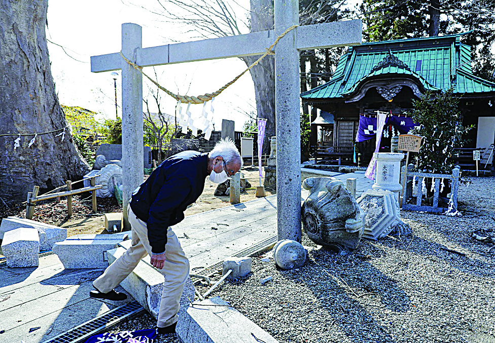 FUKUSHIMA PREFECTURE: A priest inspects the collapsed stone lanterns at a shrine in Minamisoma, Fukushima prefecture yesterday following a 7.3-magnitude quake jolted east Japan the night before. - AFPn