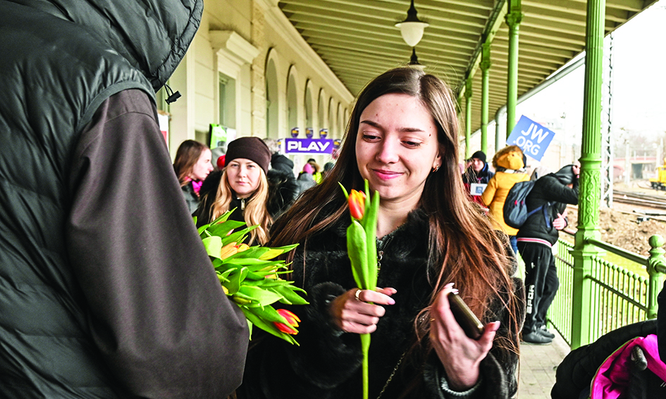 PRZEMYYL, Poland: A woman smiles as she receives a flower from a Polish priest on the occassion of the International womens' day at the train station of Przemyl where hunderds refugees from Ukraine wait for their relocation, in Przemysl, Poland. – AFPnn