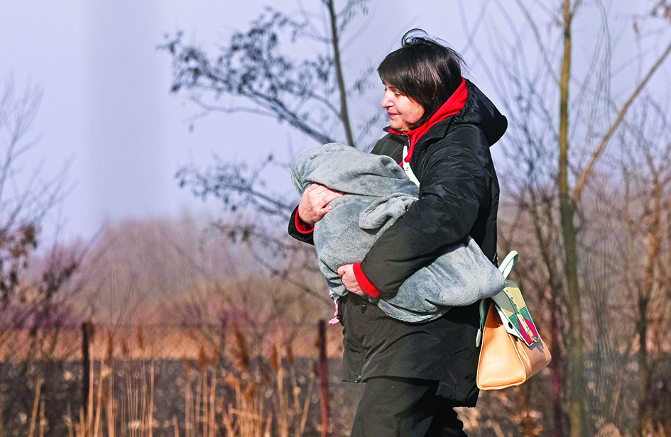 SIRET, Romania: A woman carries a child as Ukrainian refugees cross the Ukrainian-Romanian border in Siret, northern Romania. The Ukraine war has major economic consequences for energy, food, inflation and poverty, according to the European Bank for Reconstruction and Development.—AFPn