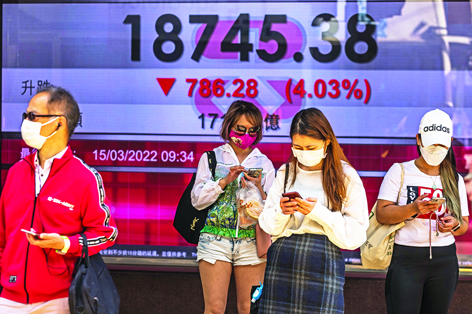 HONG KONG: People stand in front of a display showing the Hang Seng Index in Hong Kong yesterday.—AFPnn