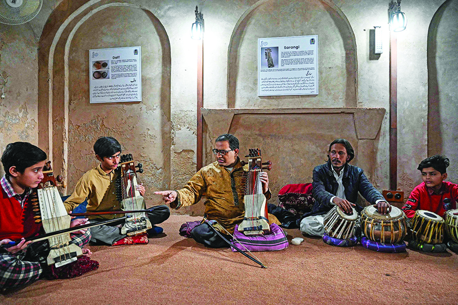 In this picture Zohaib Hassan (center) teaches his students to play sarangi at his academy in Lahore.—AFP photos