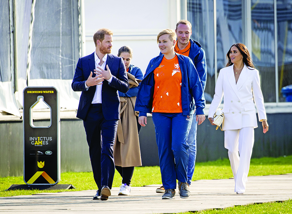 Britain’s Duke of Sussex Prince Harry (left) and his wife Duchess of Sussex Meghan (right) walk with officials on the yellow carpet ahead of The Invictus Games in The Hague on Friday.—AFP