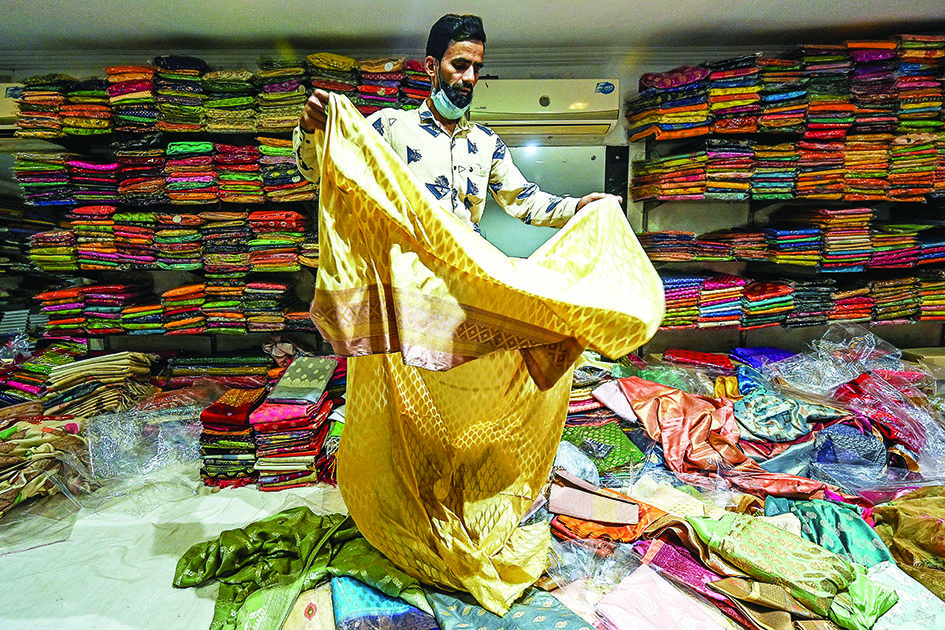 In this photograph a shopkeeper shows a traditional Banarasi sari at a store in Varanasi. – AFP photos